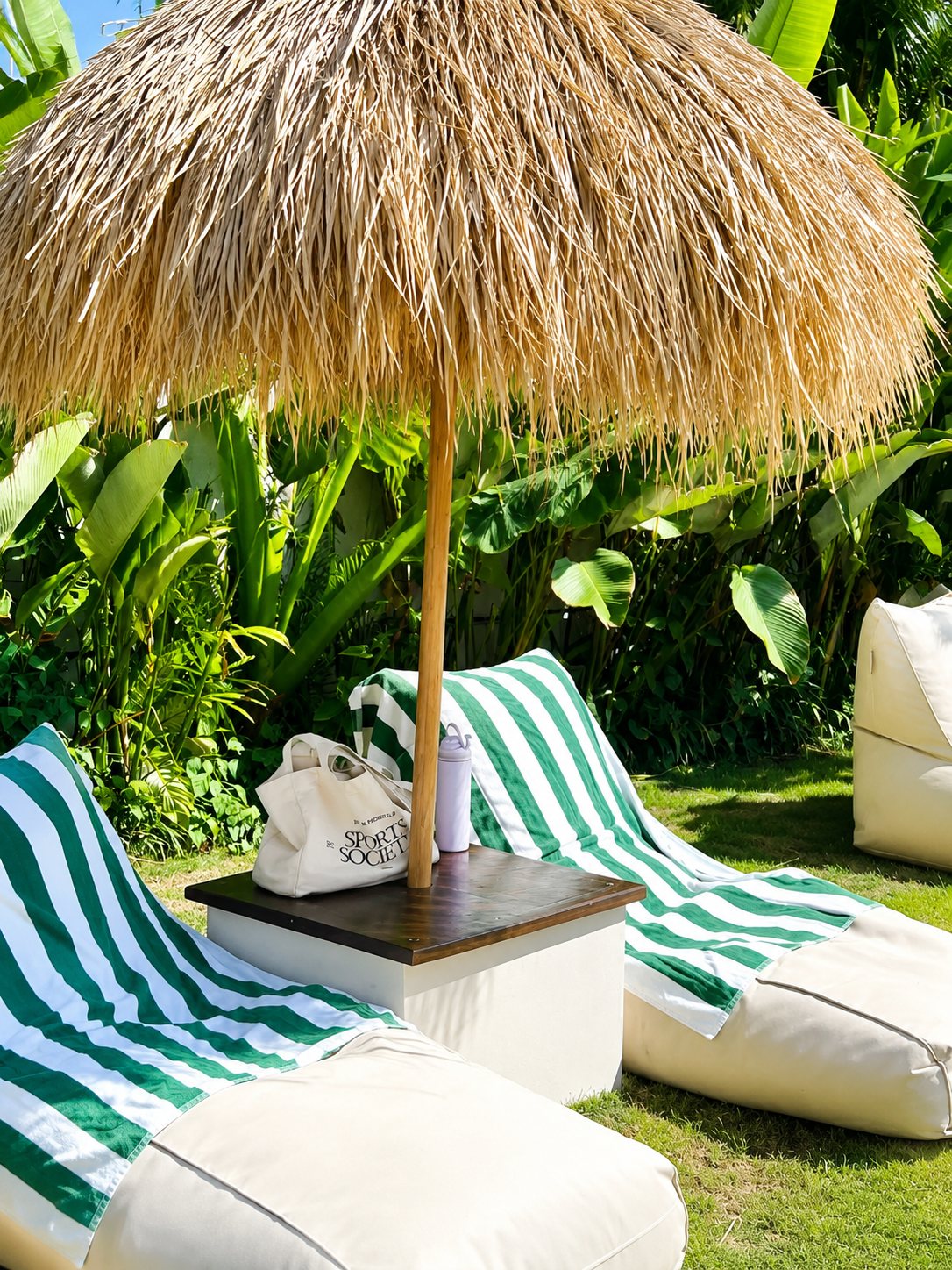 Poolside garden loungers under a thatched umbrella at Sĕni Uluwatu